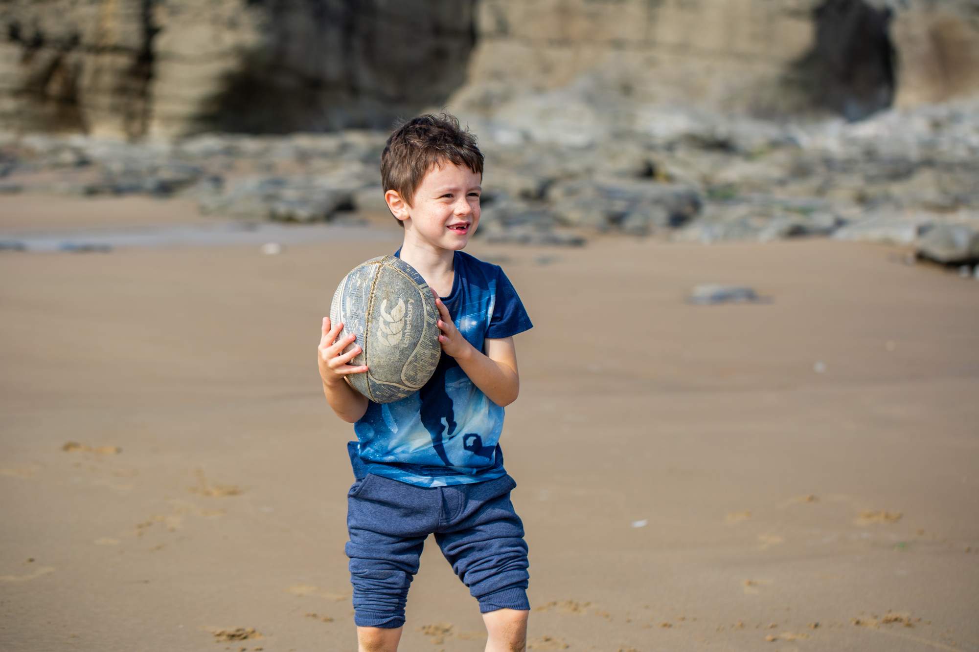 A boy holding a ball in his hands on the beach
