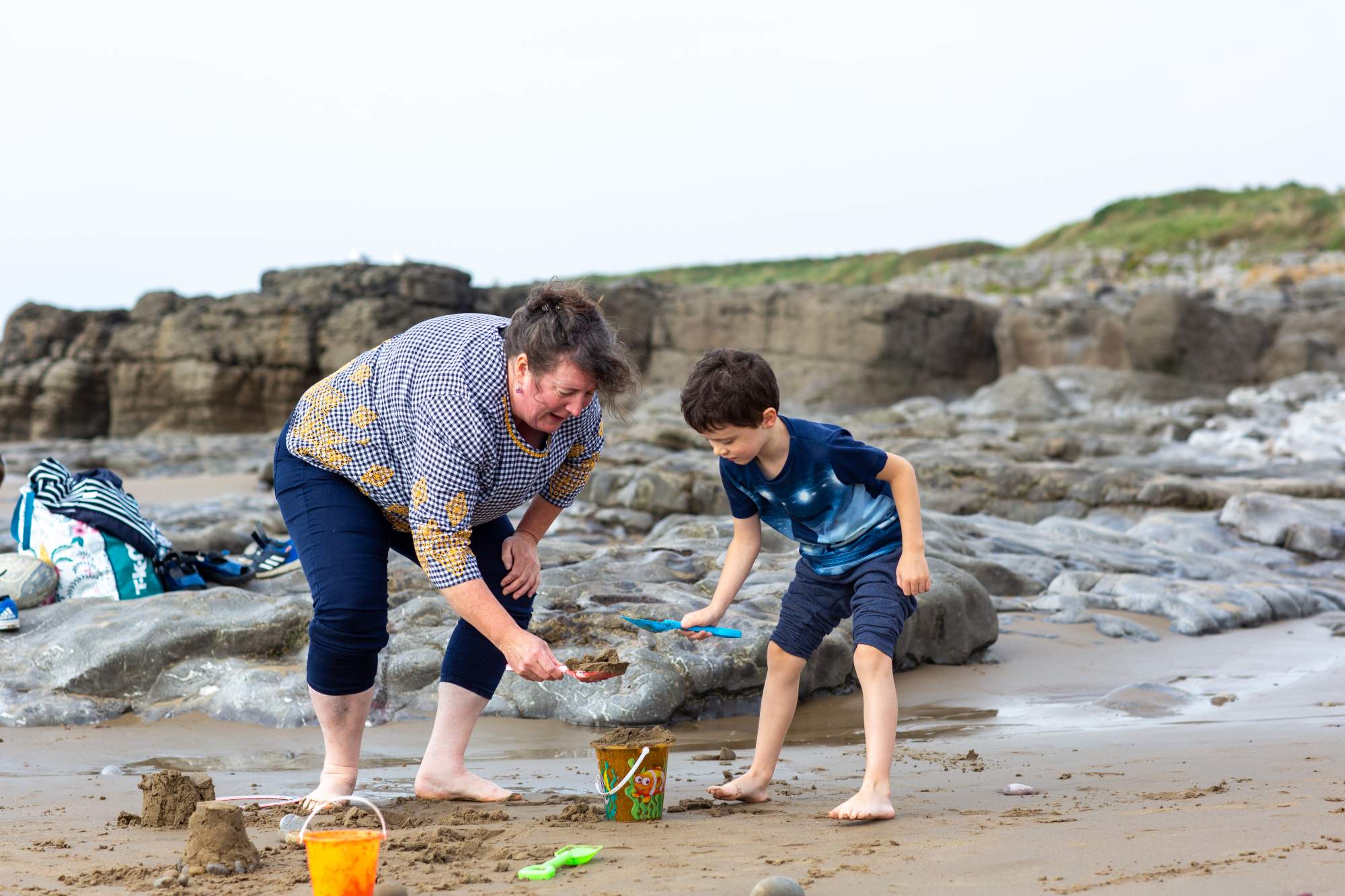A mum and her son playing in the sand on the beach