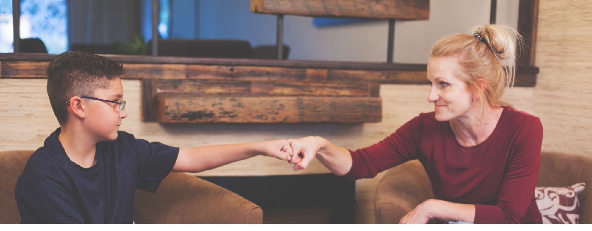 Transitional carer and male child sat down holding hands.